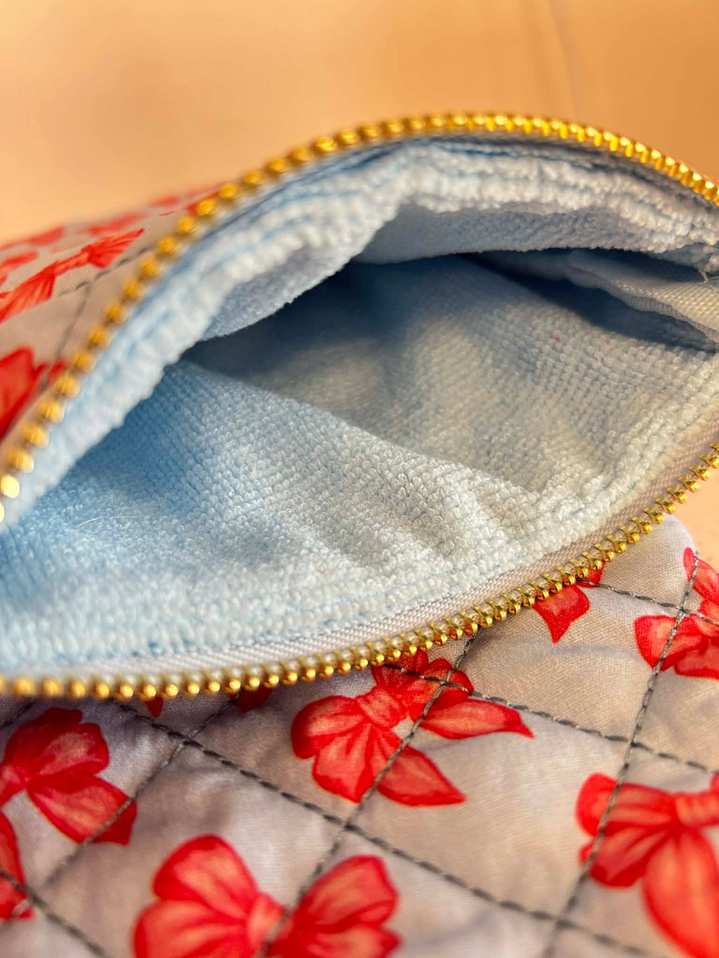 Close-up of a fabric pouch with pin bows pattern and gold zipper