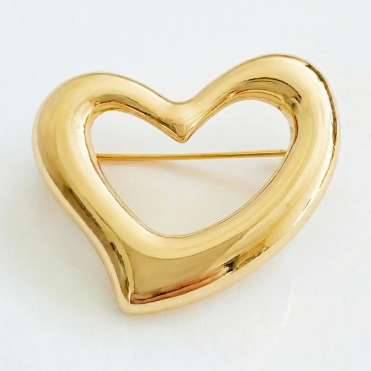 Gold heart-shaped brooch on a light gray background