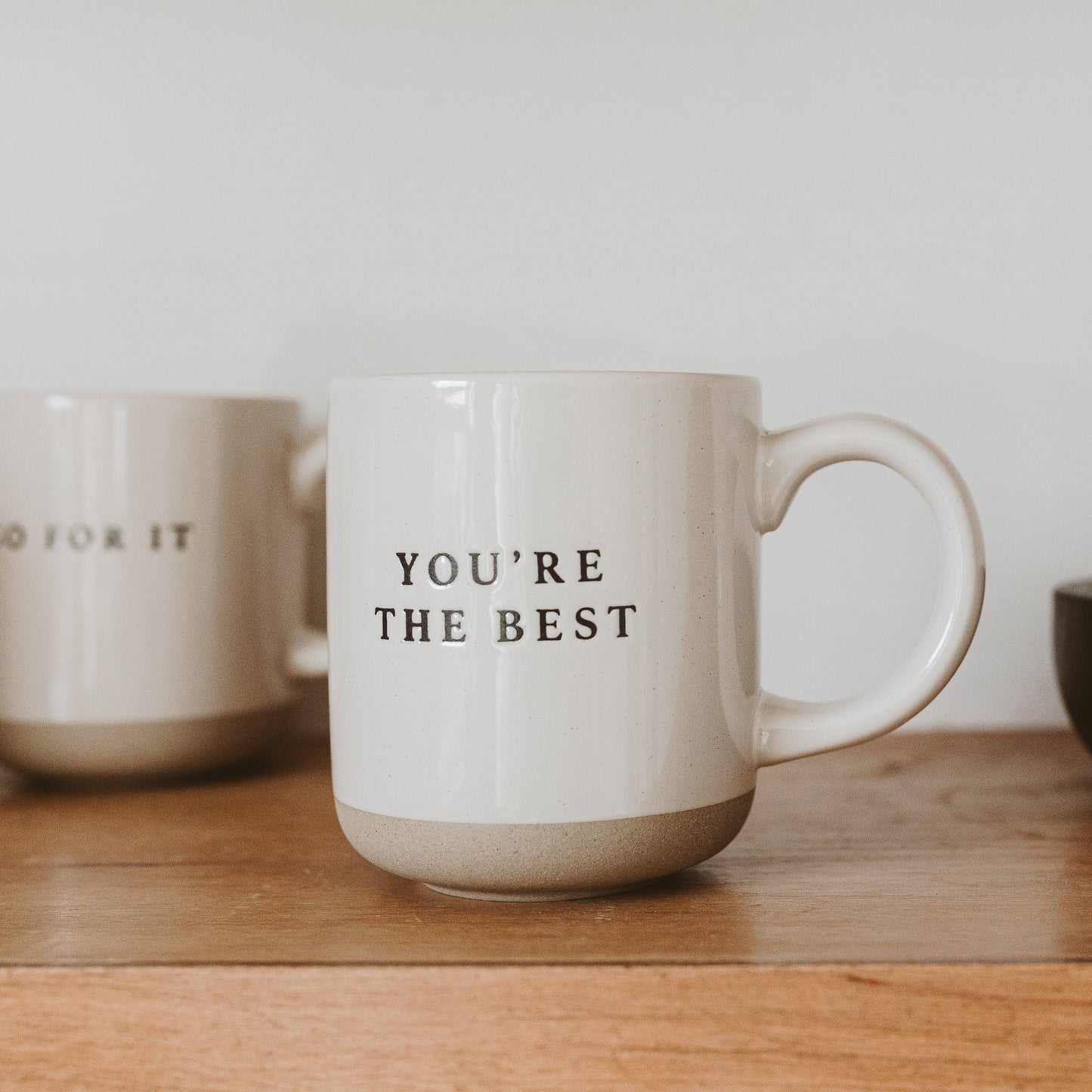 White mug with 'YOU'RE THE BEST' text on a wooden surface