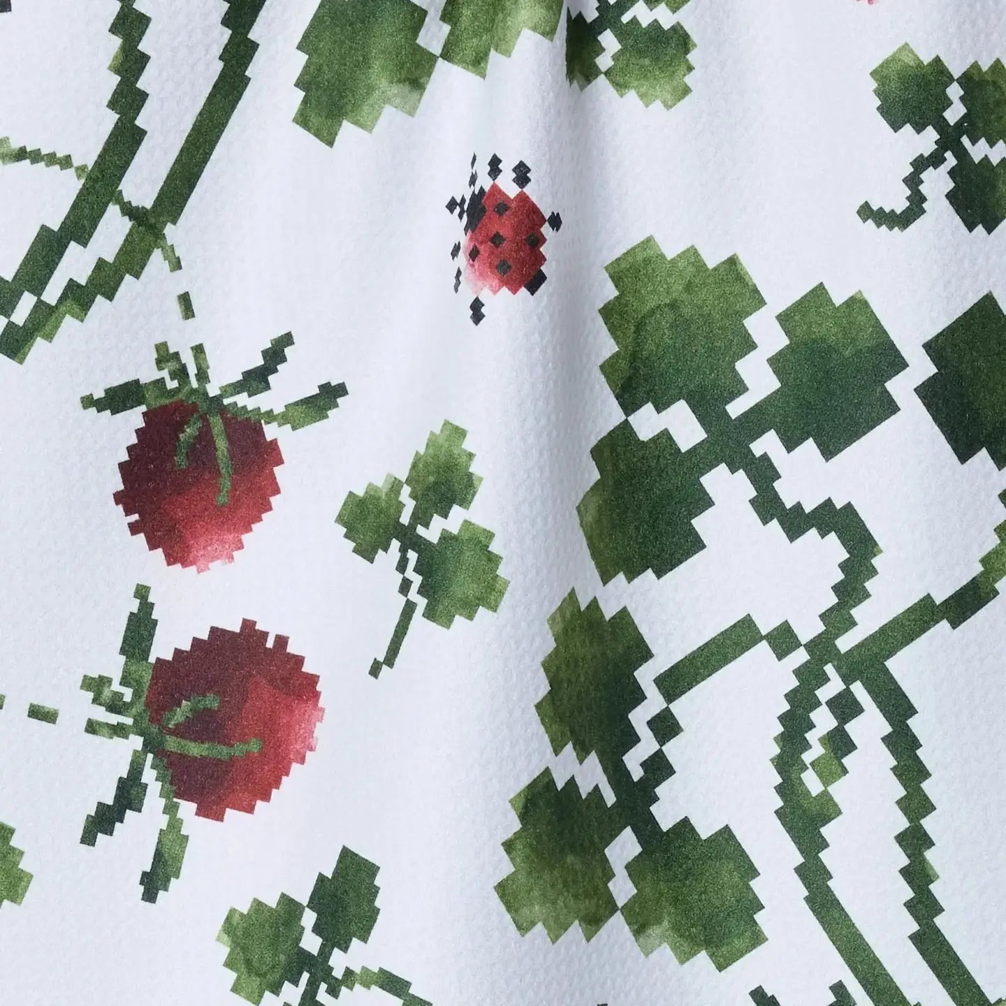 Close-up of a fabric with pixelated strawberry and leaf pattern on a white background