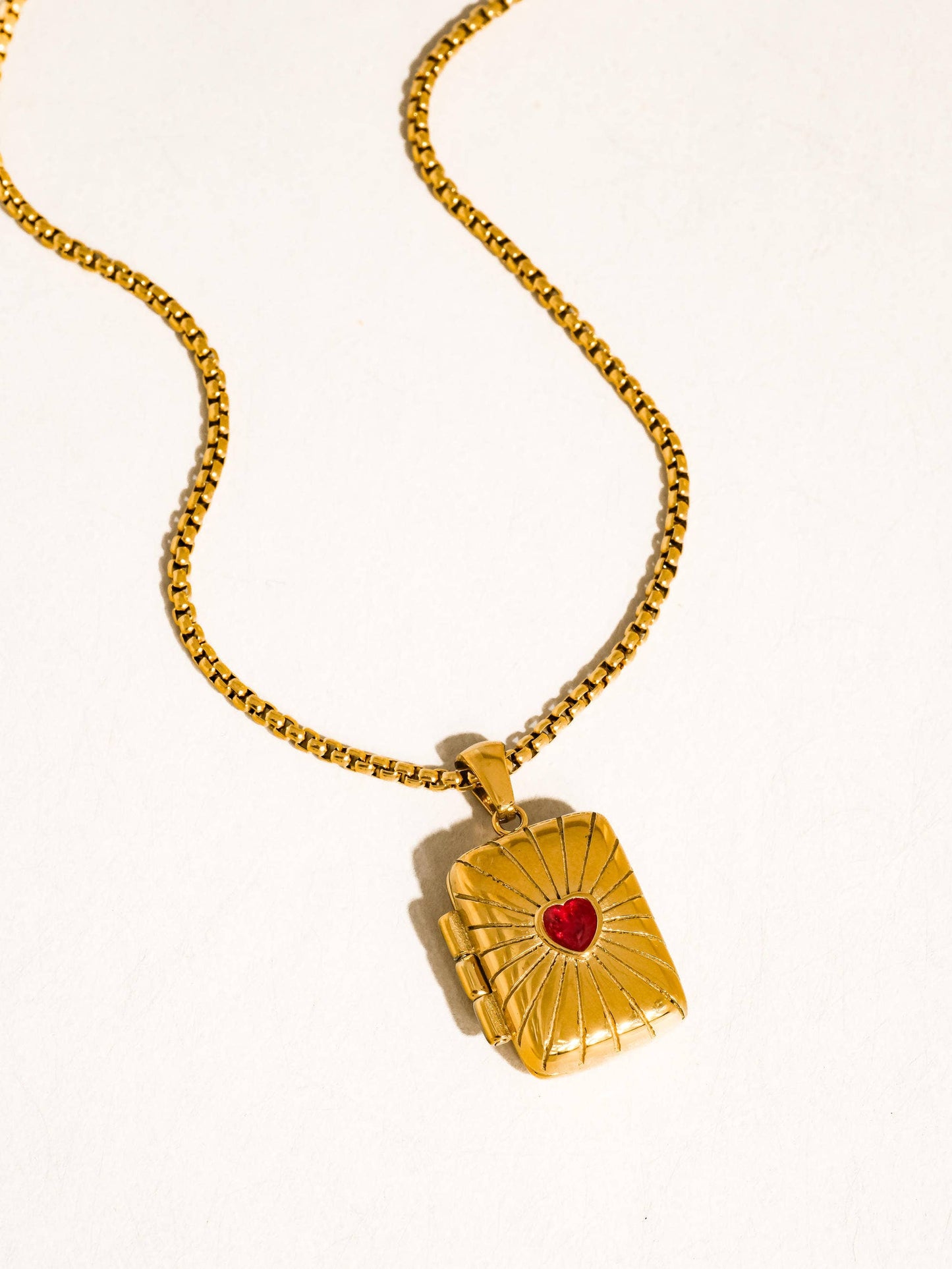 Gold necklace with a heart-shaped pendant on a white background