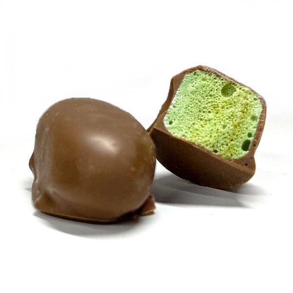 mystery crunchers chocolate coated candy with a green interior sitting on a white background
