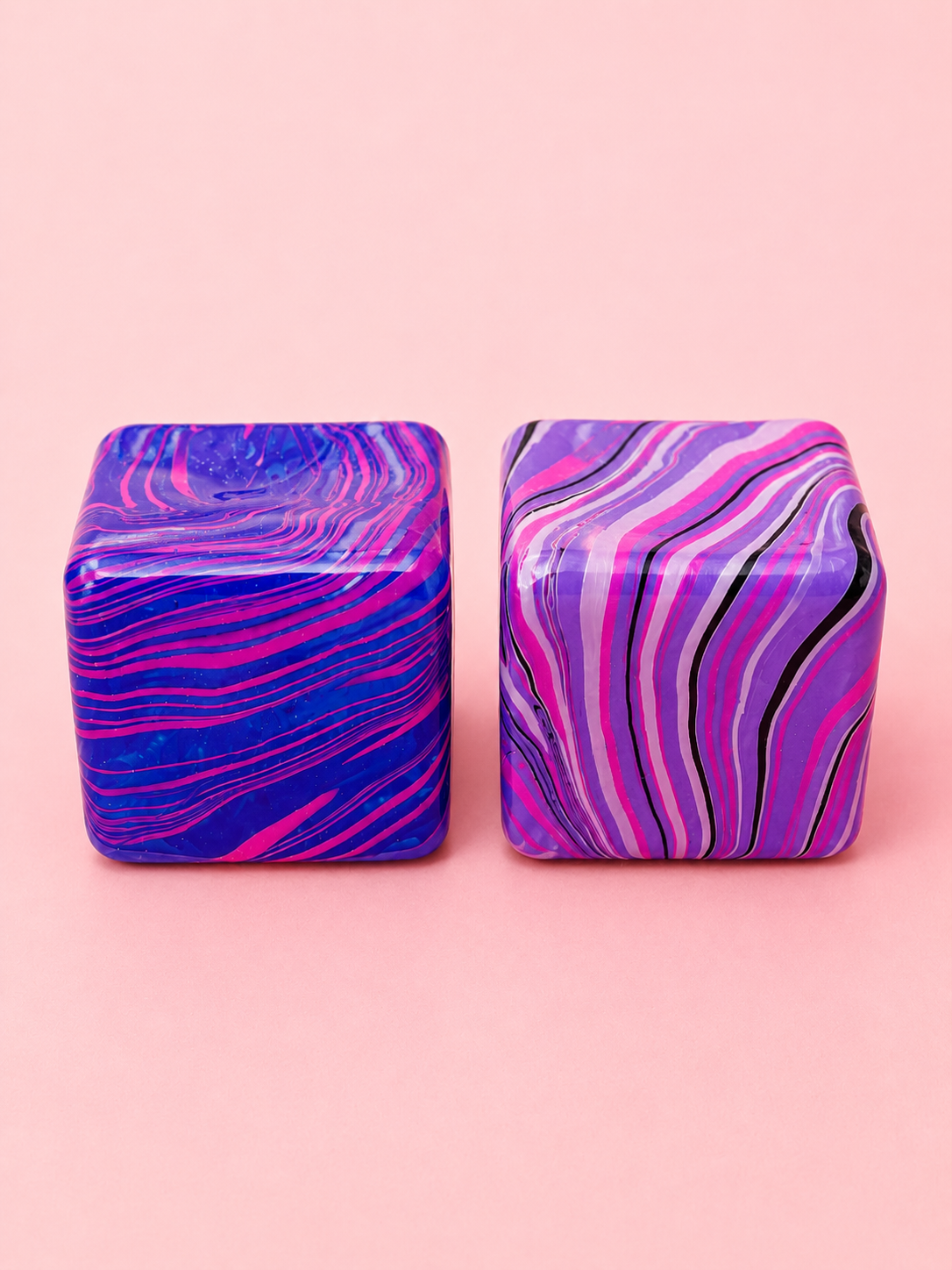 Two marbled square containers with purple and pink swirls on a pink background
