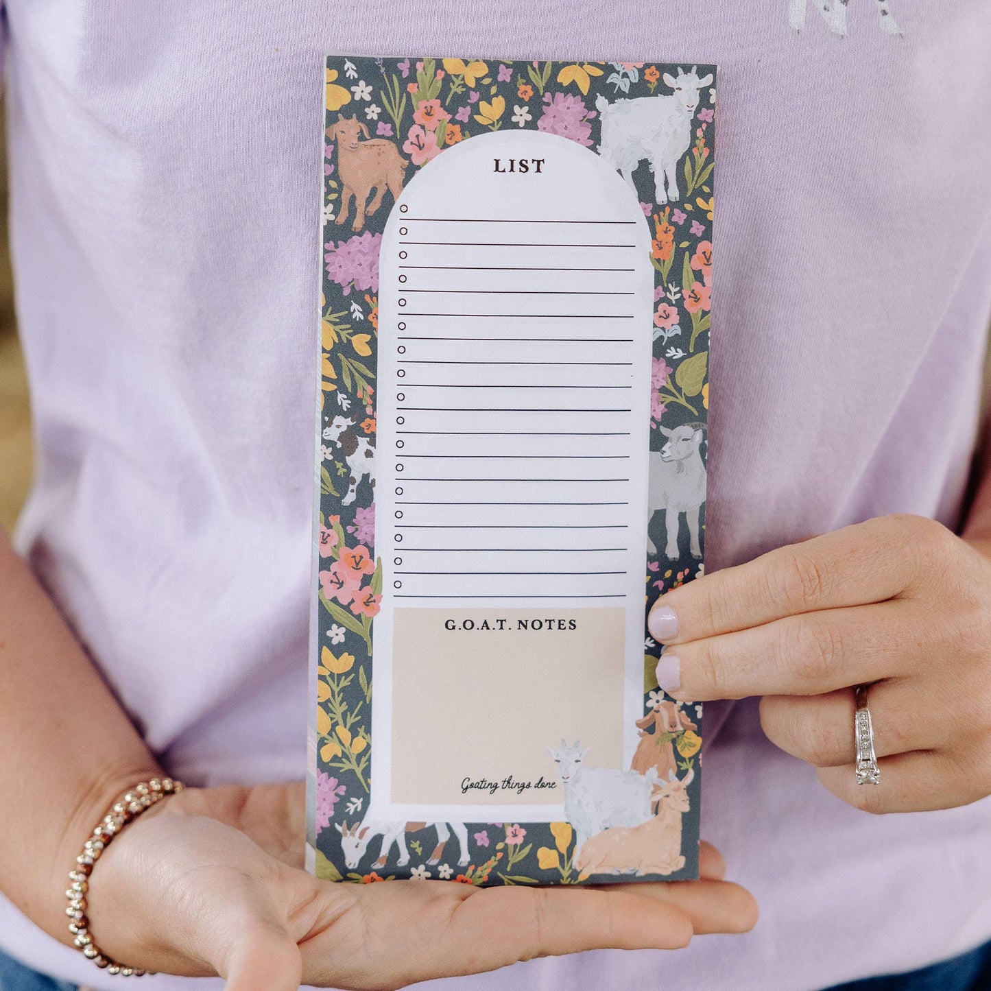 goat floral notepad held by a pair of hands