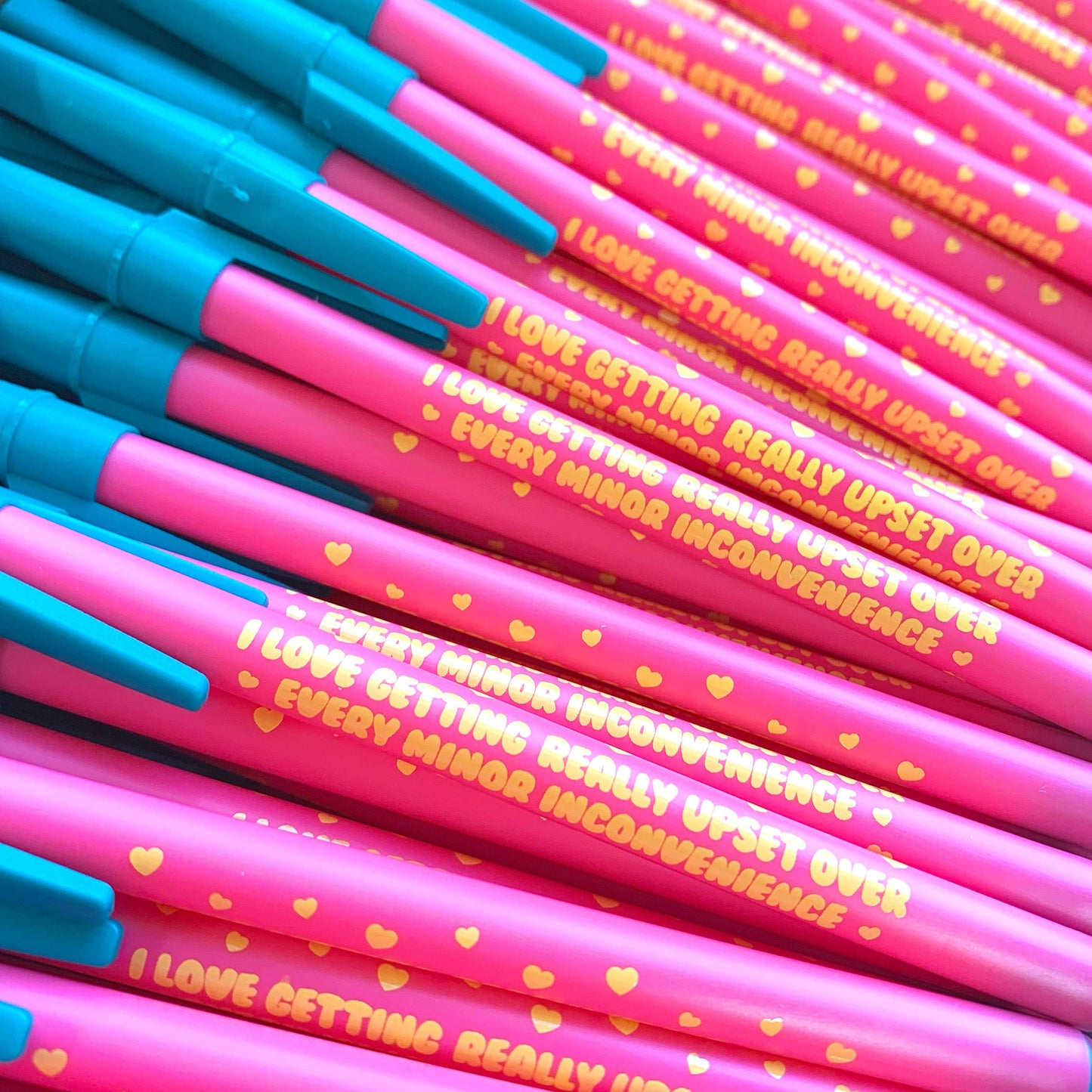 Pink and blue pens with humorous text and heart designs.