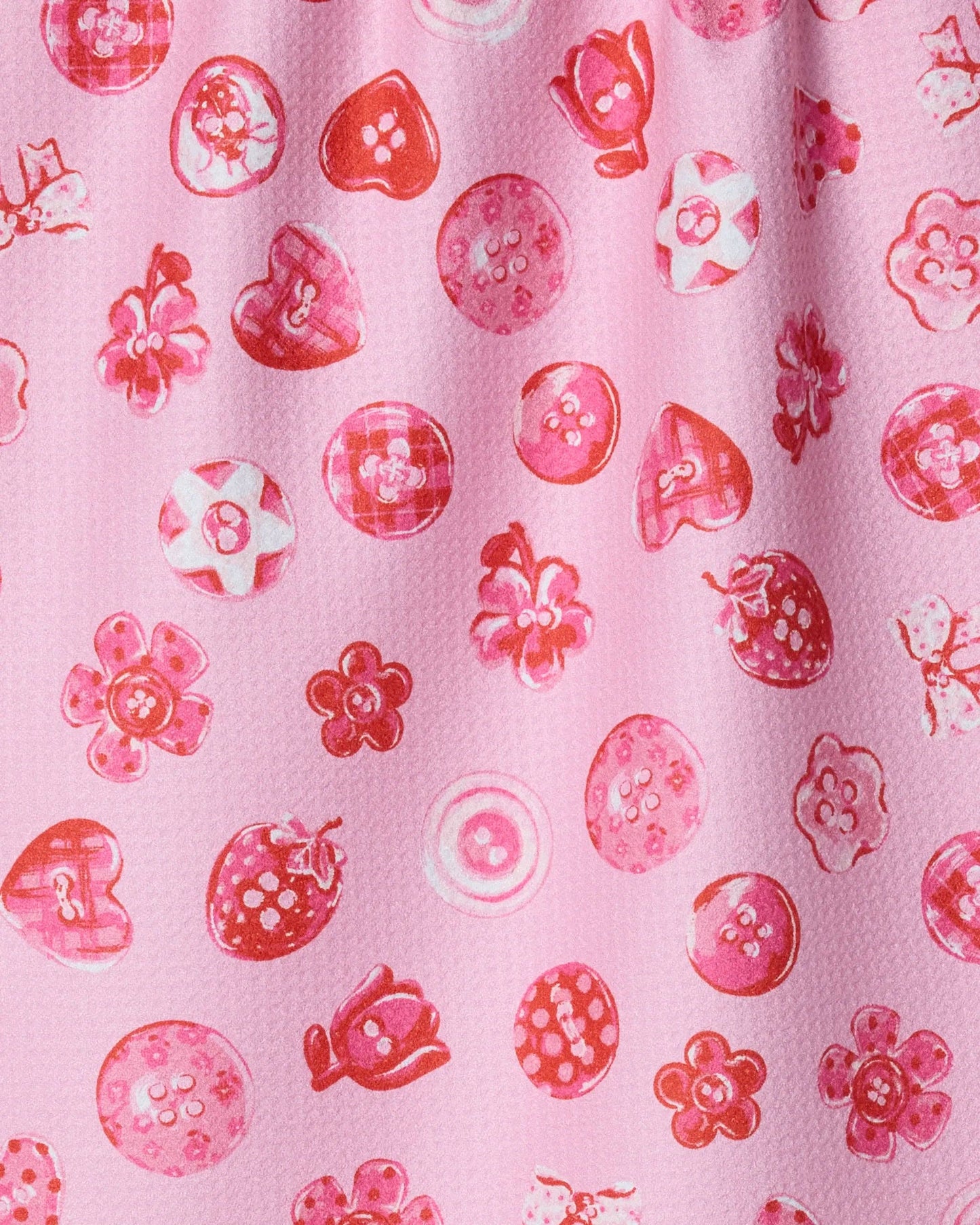 Pink tea towel with buttons design. Buttons are shaped like hearts, strawberries, flowers, and circles