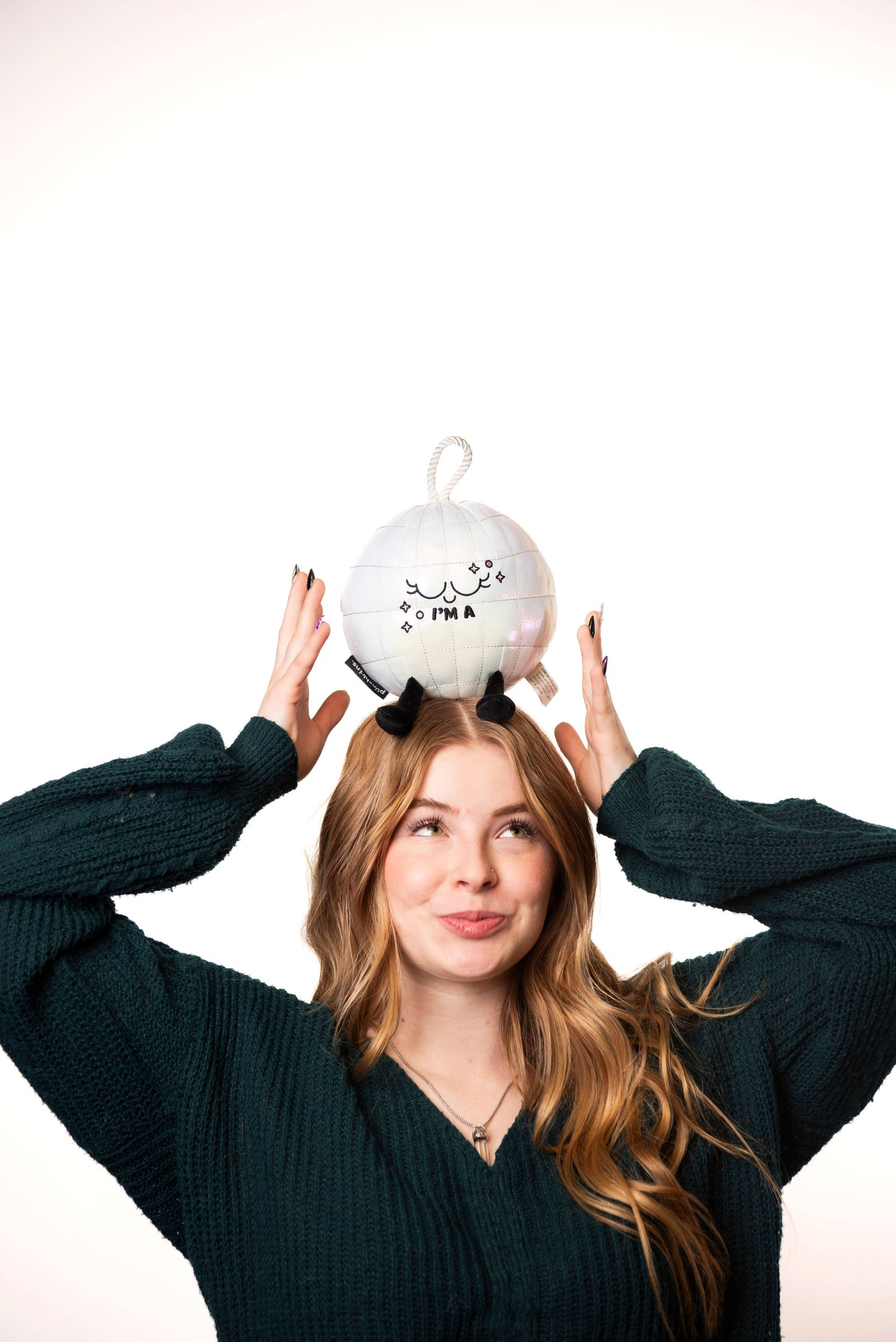 Person with a disco ball plushie on their head on a white background