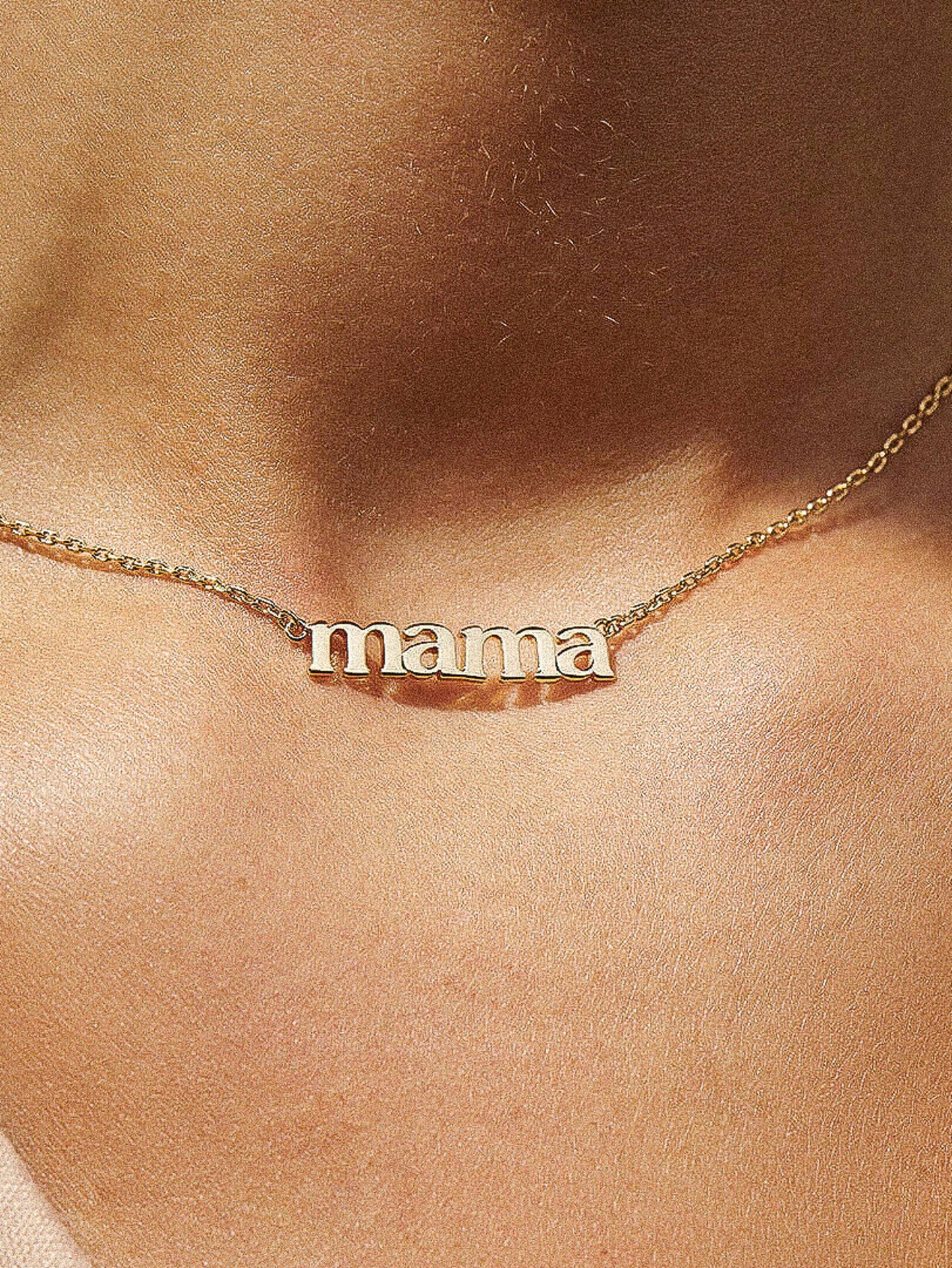 Gold 'mama' necklace on a person's neck