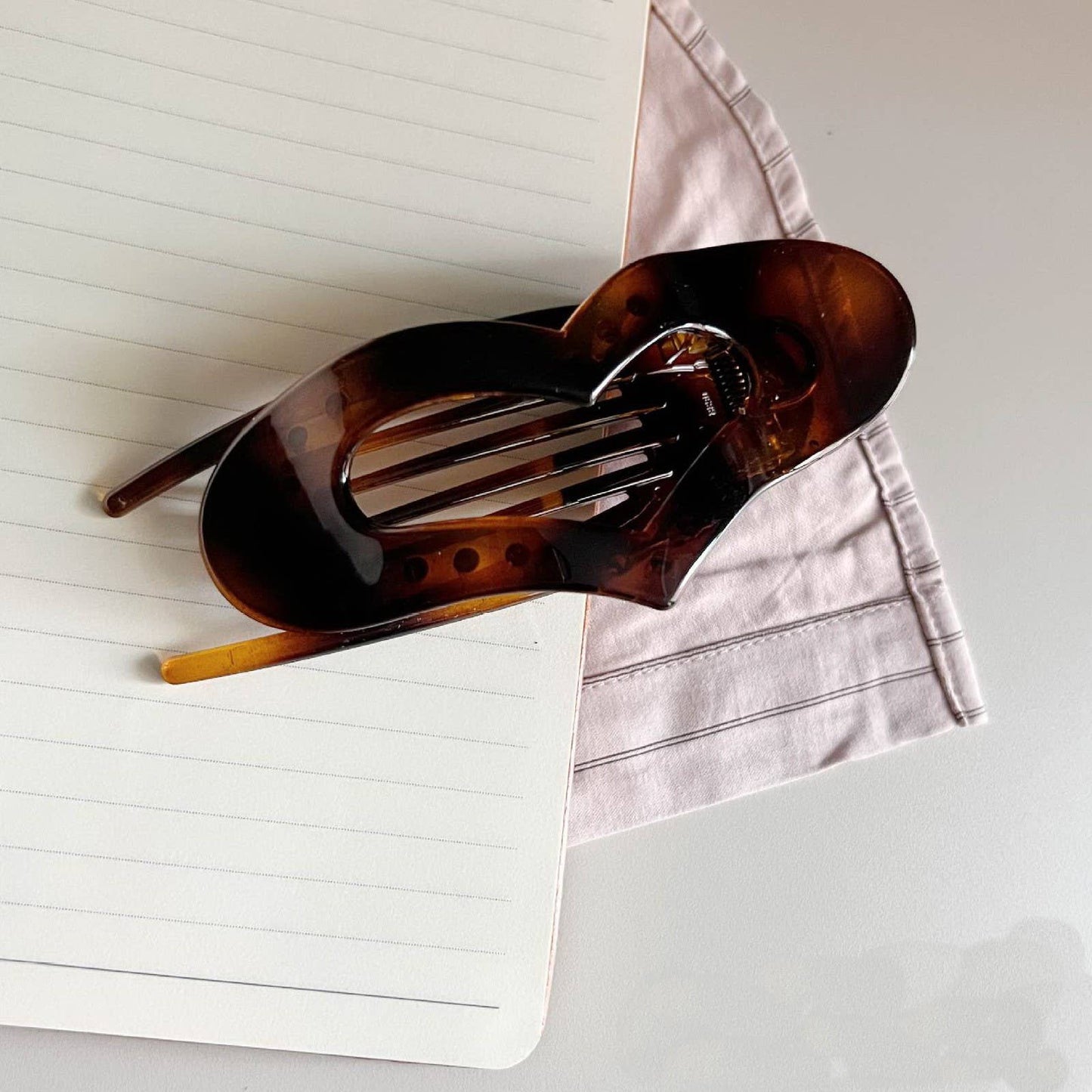 Tortoise shell, heart shaped "lay-flat" claw clip on an open notebook