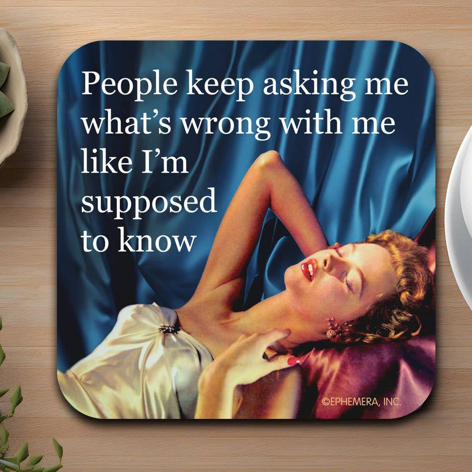 Coaster with a quote that reads "People keep asking me what's wrong with me like i'm supposed to know" and an image of a woman lying on a blue fabric background.