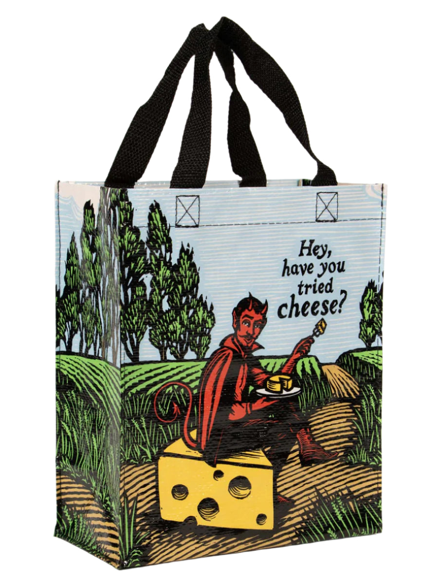 Tote bag with a devil character eating cheese in a field with text that says "Hey, have you tried cheese?"