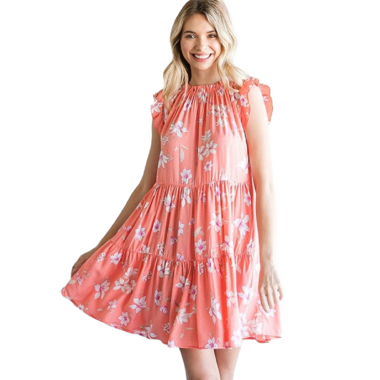 Pictured is a coral dress with white flowers. Featuring a shirred neck, ruffled flutter sleeves, and 3 tiers.