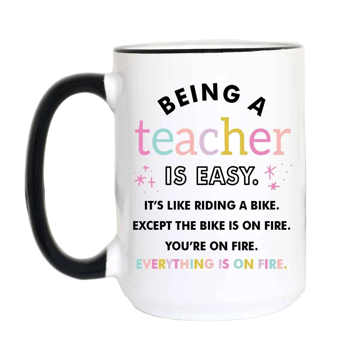 White mug with colorful textreading "Being a teacher is easy. It's like riding a bike. Except the bike is on fire. You're on fire. Everything is on fire" on a white background