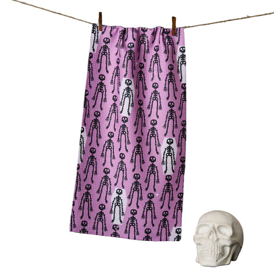 Purple towel with skeleton pattern hanging on a line, next to a white skull.