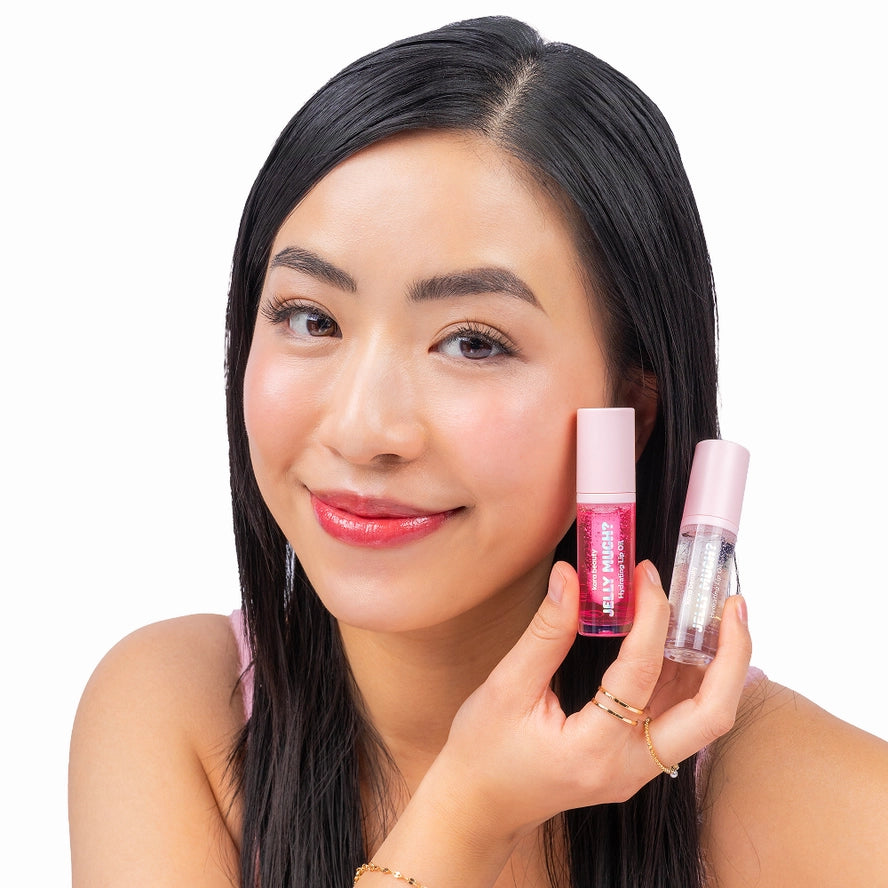 a model holding two tubes of Jelly Much lip oil and wearing the watermelon color of the product.