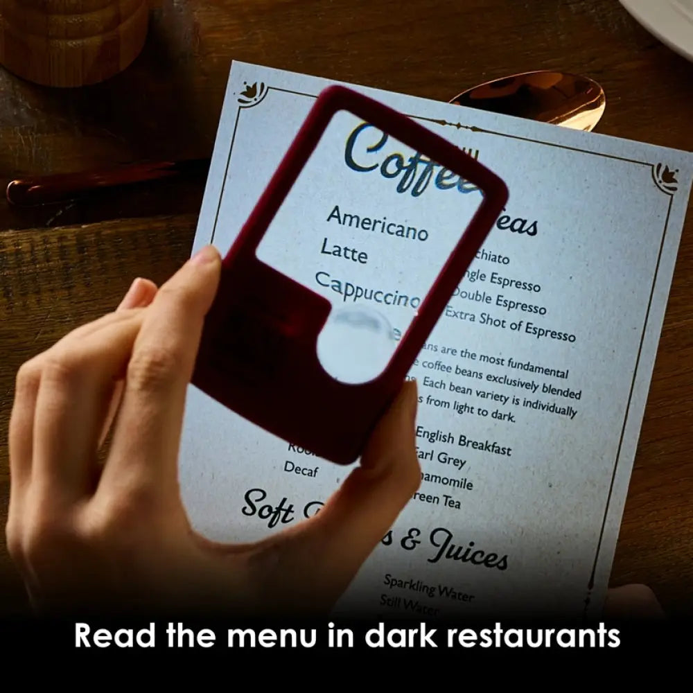 Hand using a magnifying glass to read a menu in a dark restaurant setting