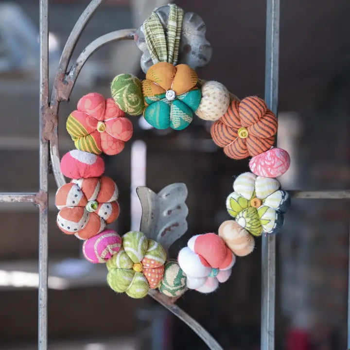 Colorful fabric flower wreath on a metal gate