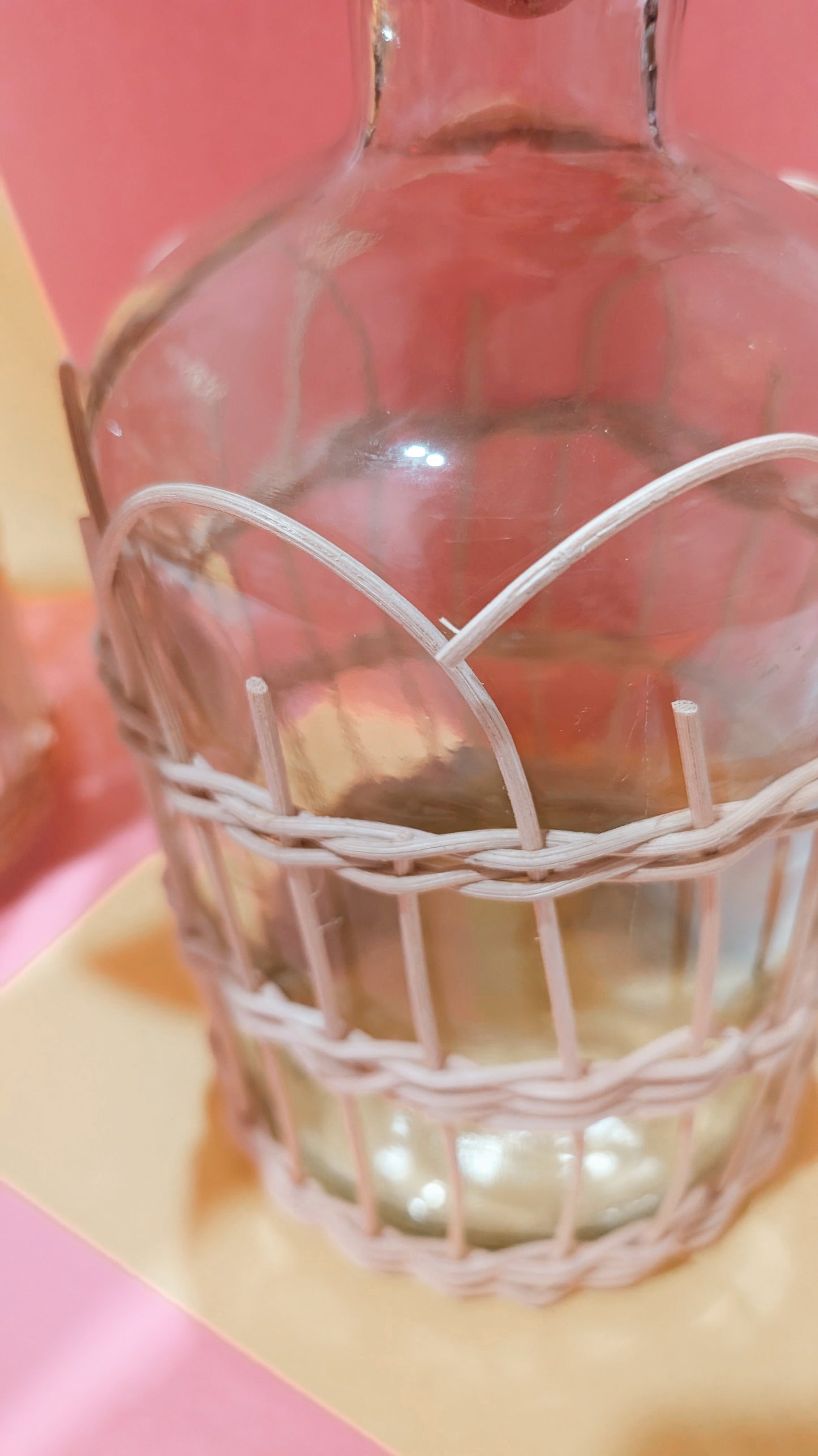 Decorative glass bottle with a wire cage on a pink background