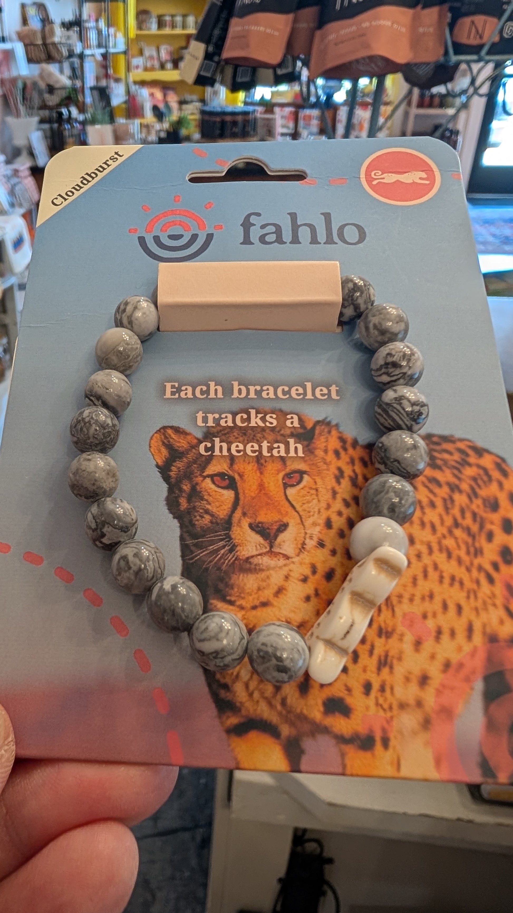 Bracelet with cheetah design on packaging, held in a hand.