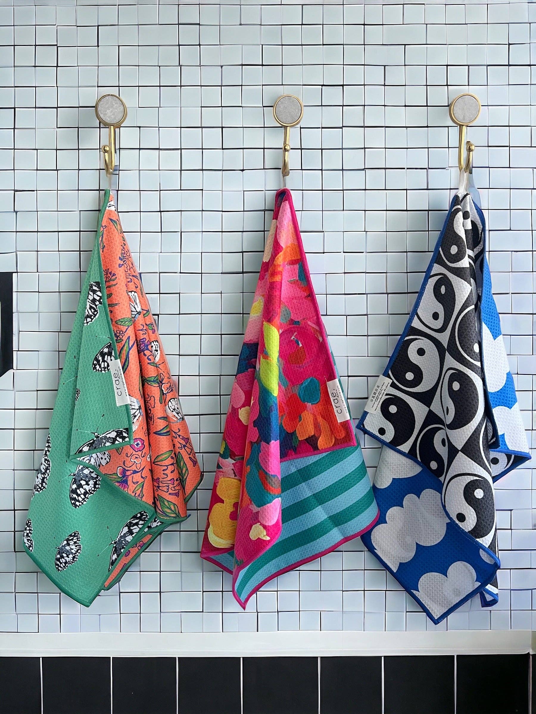Colorful patterned towels hanging on a tiled wall