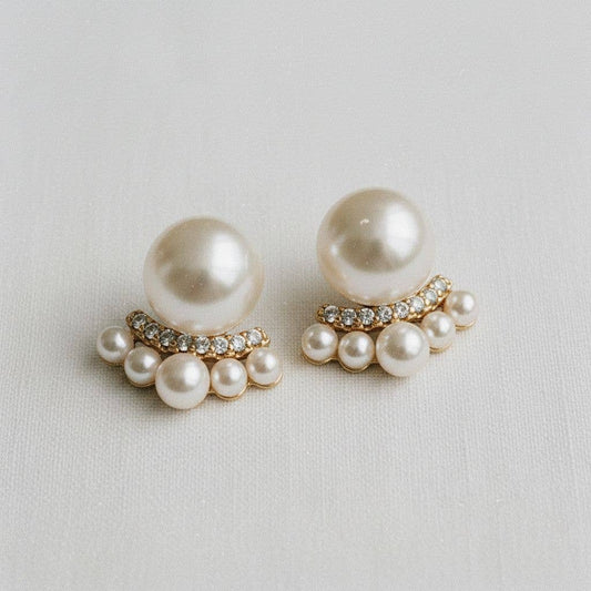 Pair of pearl earrings with gold accents on a light gray background