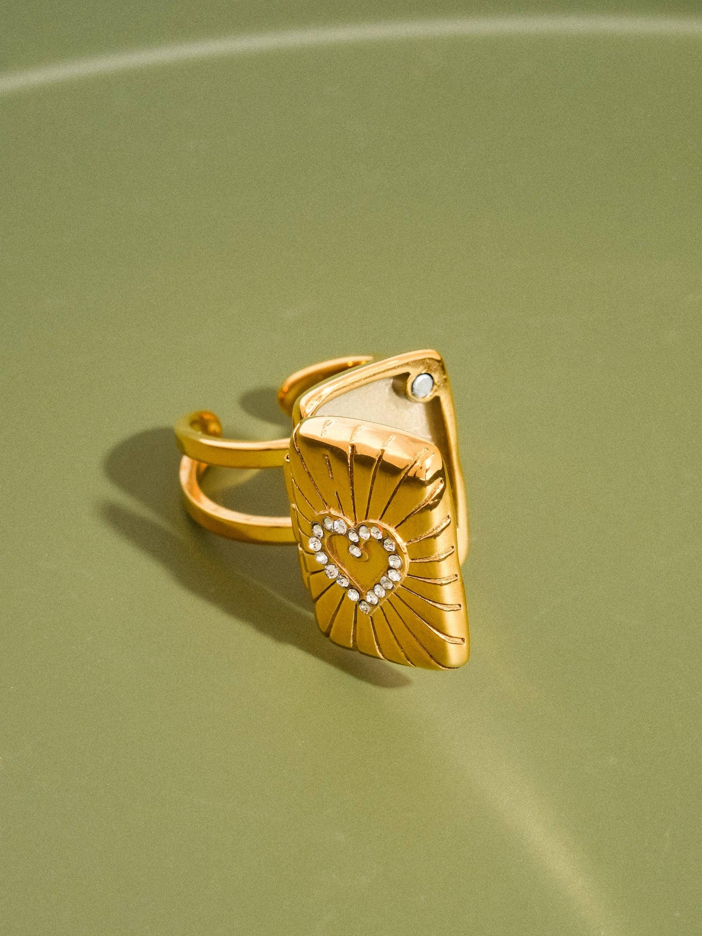 Gold ring with a heart design on a green background