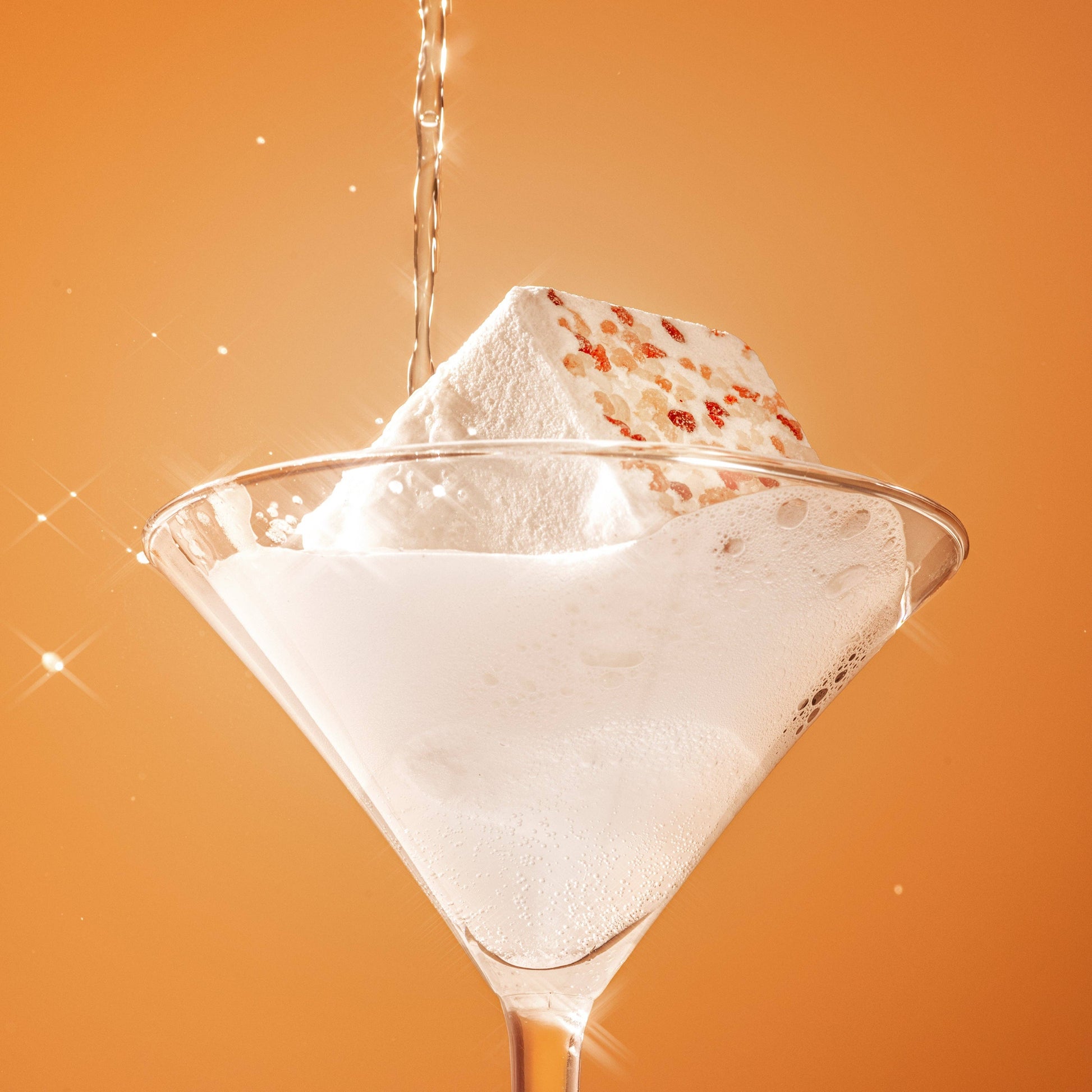 Fizzy bath bomb in martini glass with water poured over it