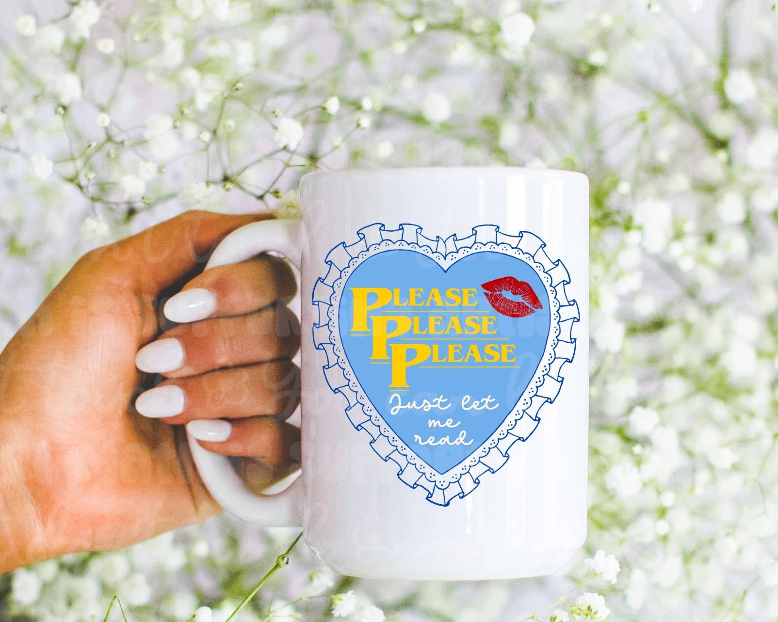 Hand holding a mug with a heart design and text against a white flower background
