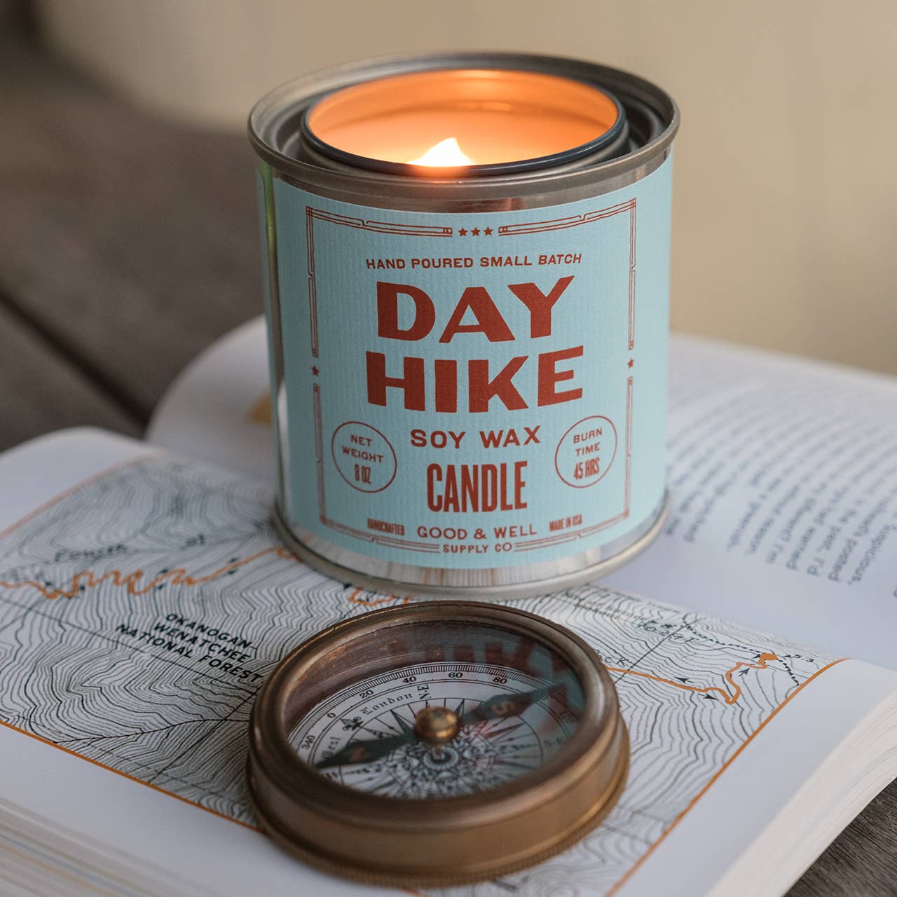 Day Hike soy wax candle in a metal canister on a map with a compass