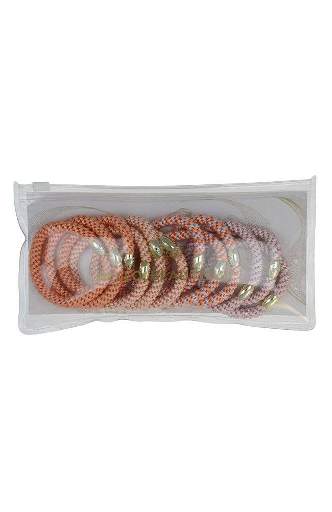 Set of pearl and gold bracelets in a clear plastic packaging on a white background
