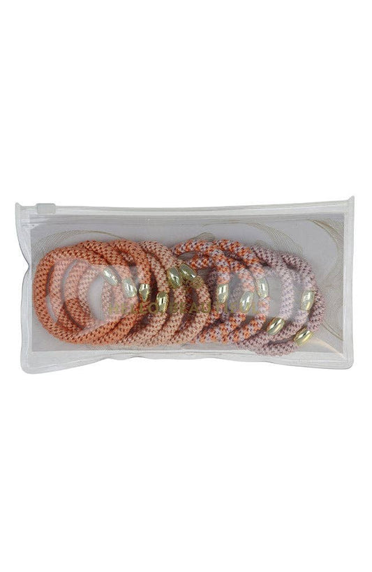 Set of pearl and gold bracelets in a clear plastic packaging on a white background