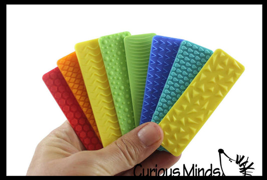 Set of colorful textured silicone mats held by a hand, with 'Curious Minds' branding.