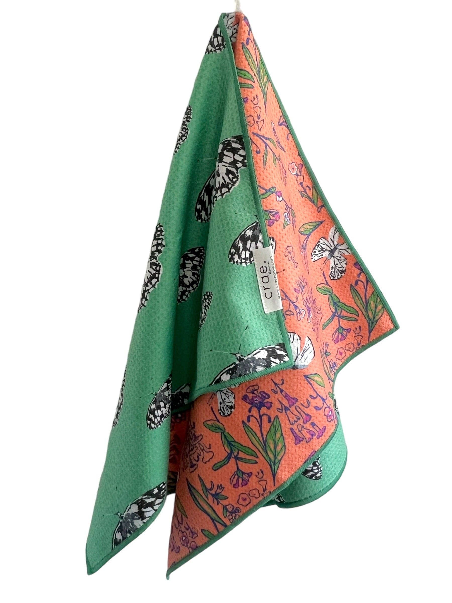 Two patterned scarves, one green with black butterfly design and the other orange with floral design, on a white background.