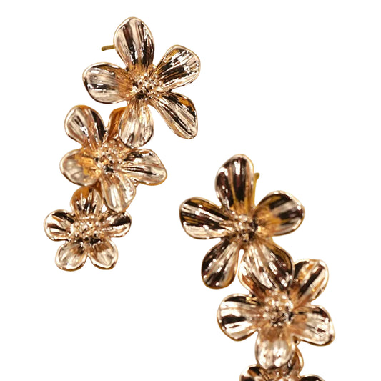 Two gold earrings, made up of 3 stacked gold flowers, on a white background