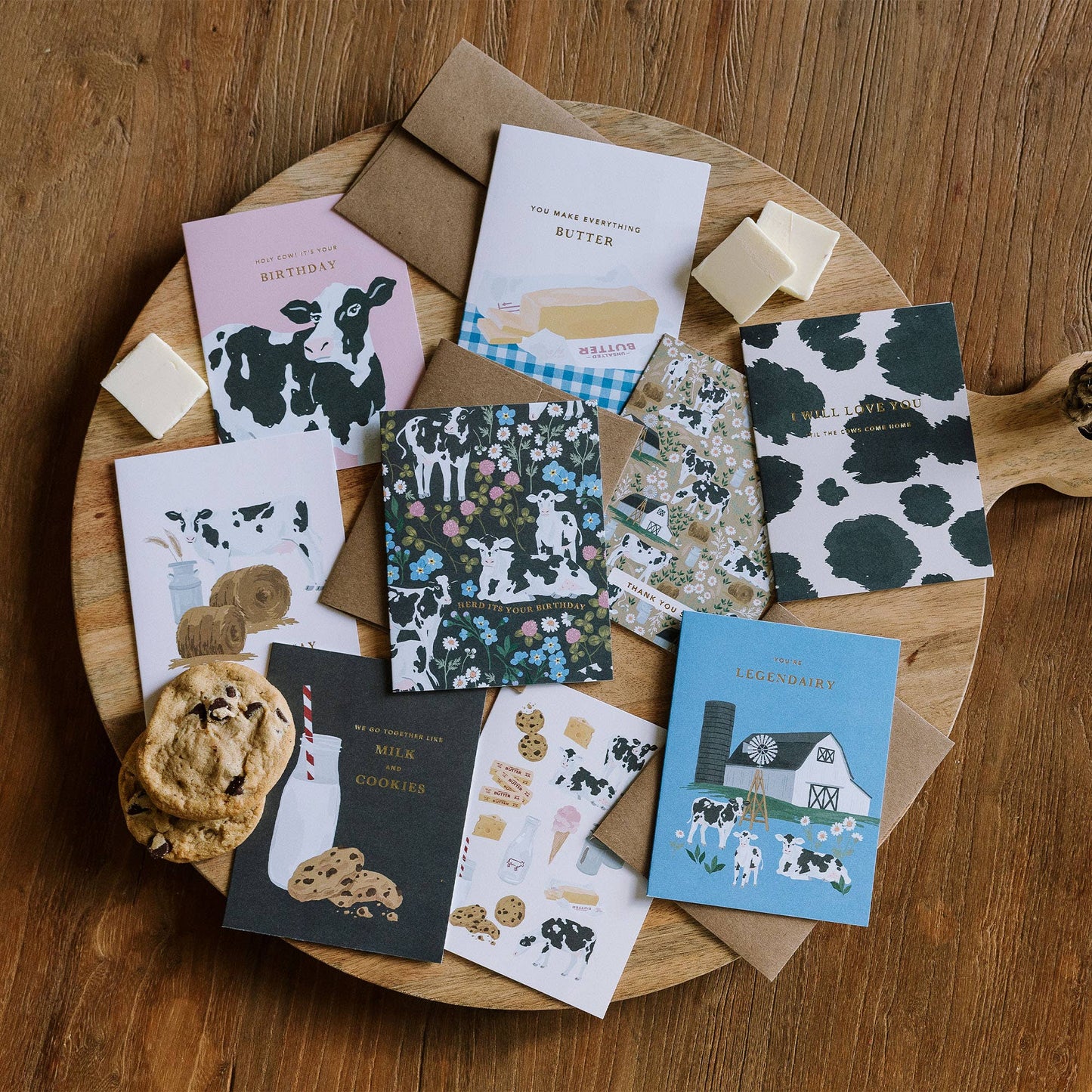 Collection of greeting cards with cow designs on a wooden tray