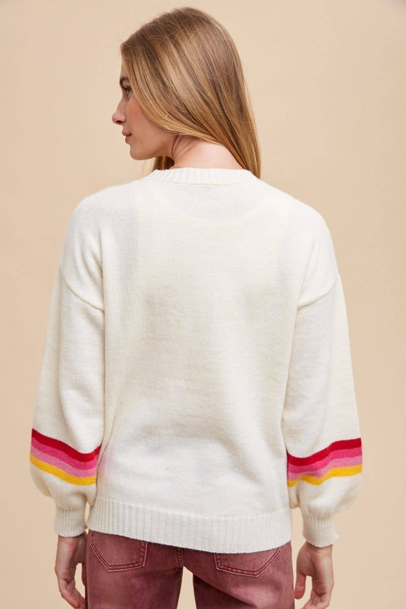 Back of a woman wearing an ivory sweater with 4 red, hot pink, light pink, and yellow stripes around the sleeves