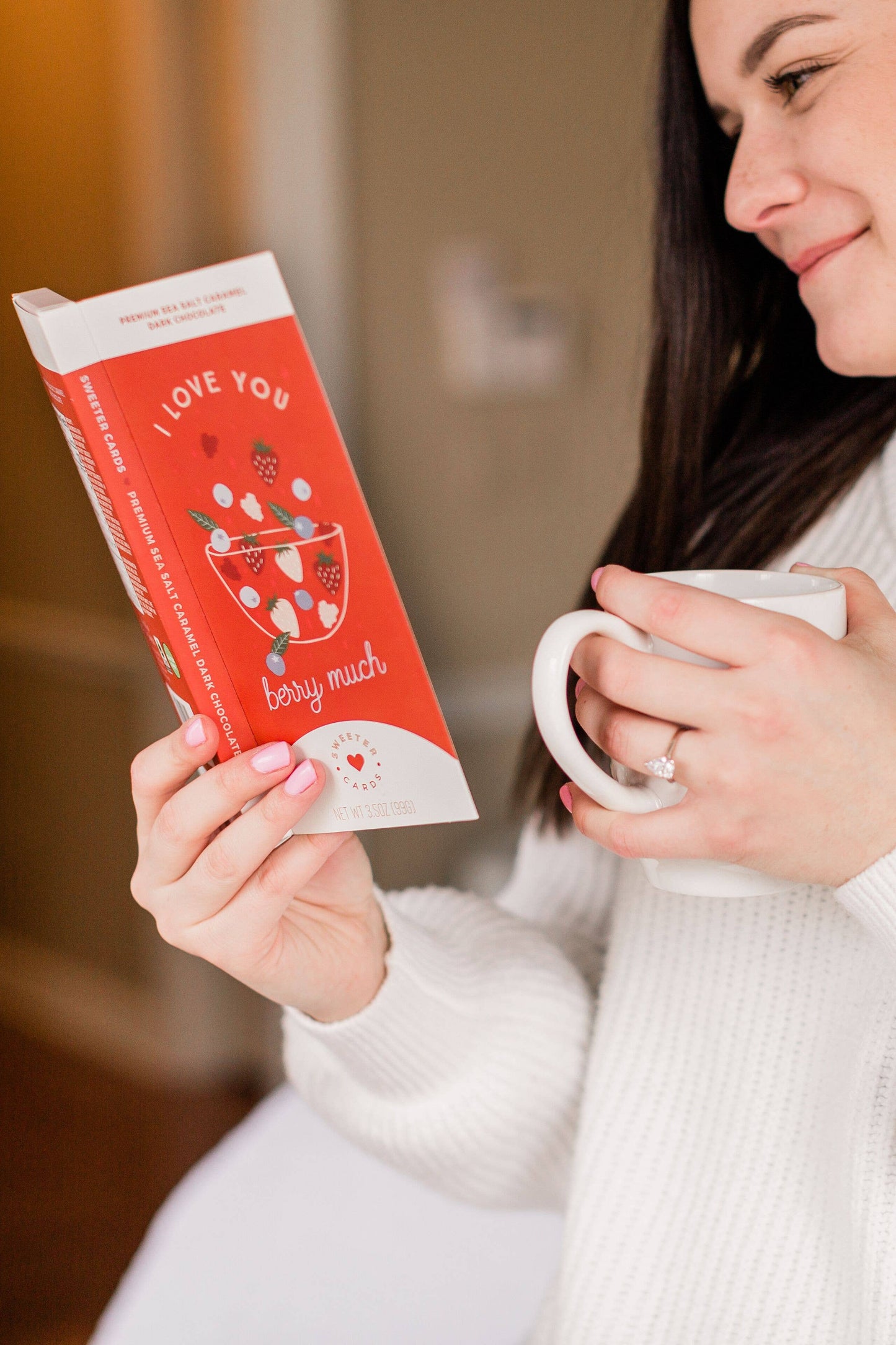 Woman holding a red package labeled 'I love you very much' and a white mug.