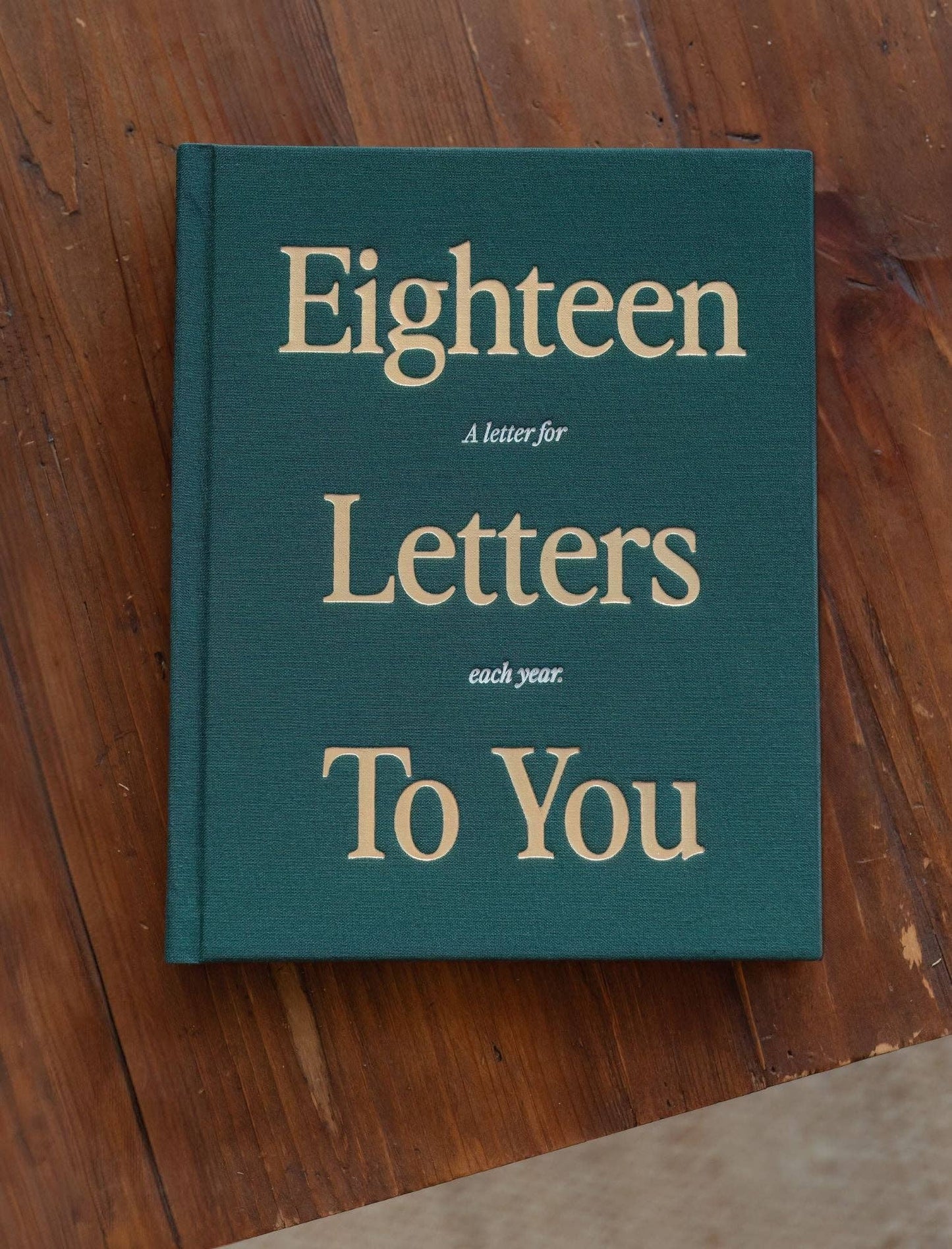 Book titled 'Eighteen Letters to You' on a wooden surface