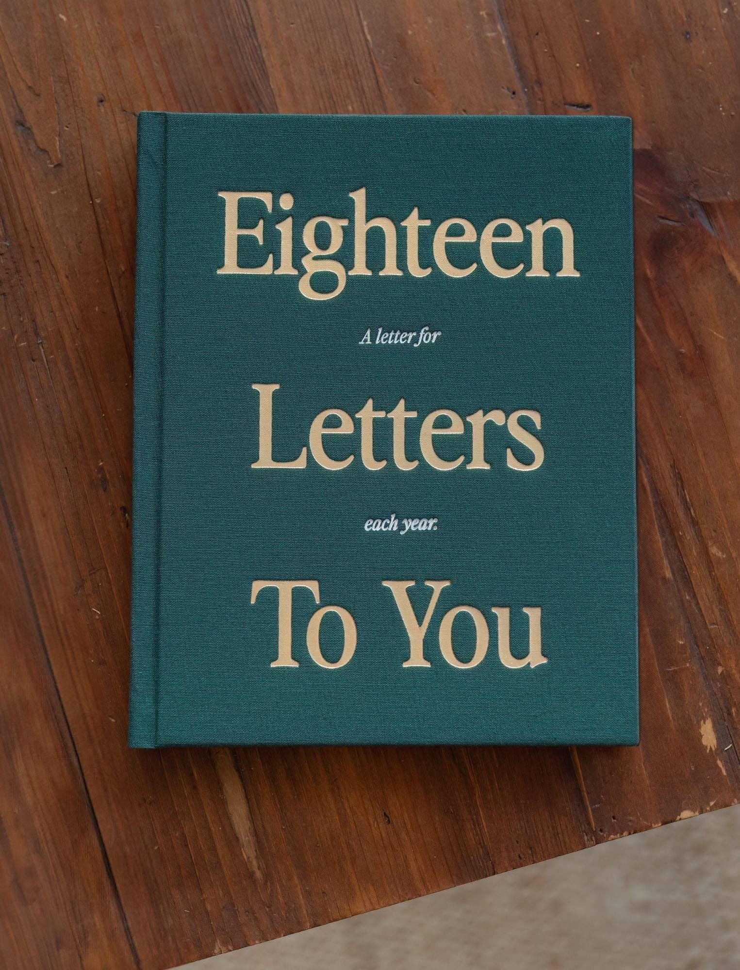 Book titled 'Eighteen Letters to You' on a wooden surface