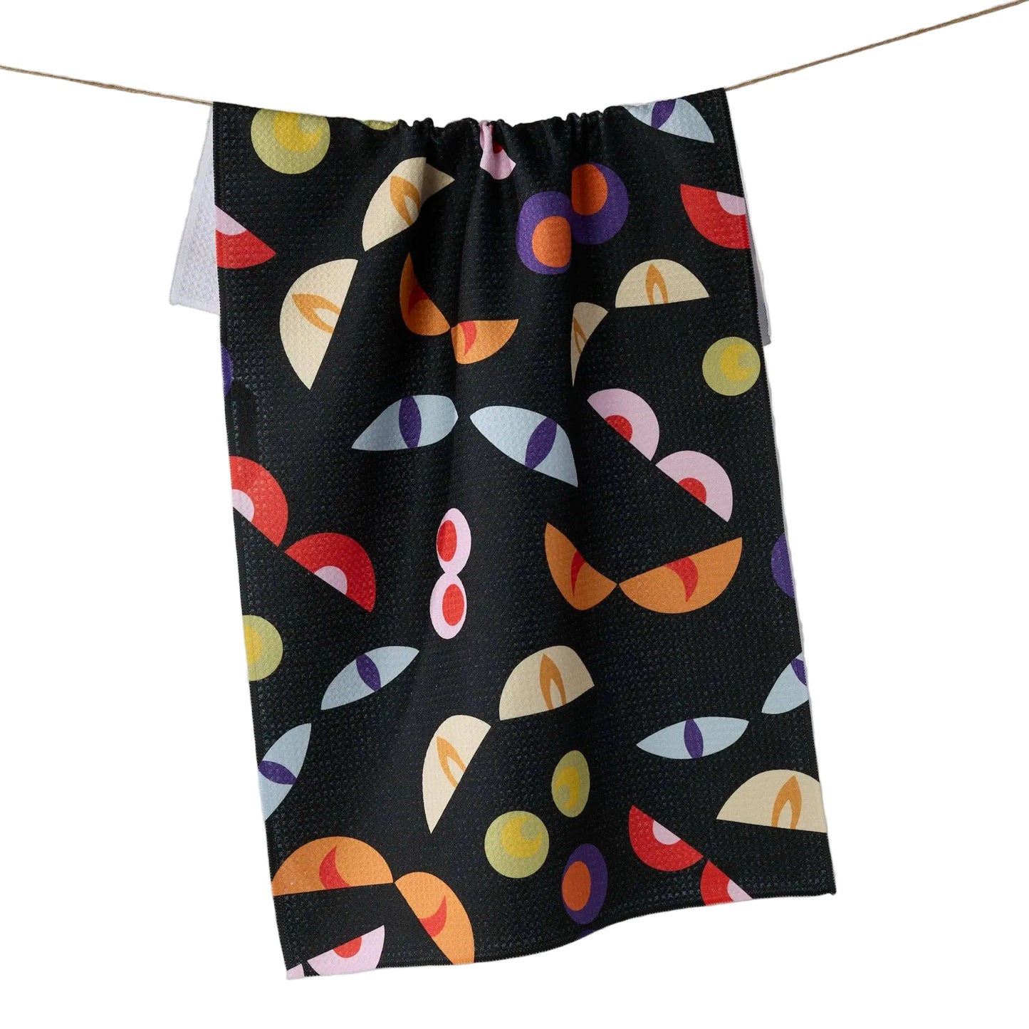 A black kitchen towel with a colorful monster eyes pattern, hanging from a string against a white background.