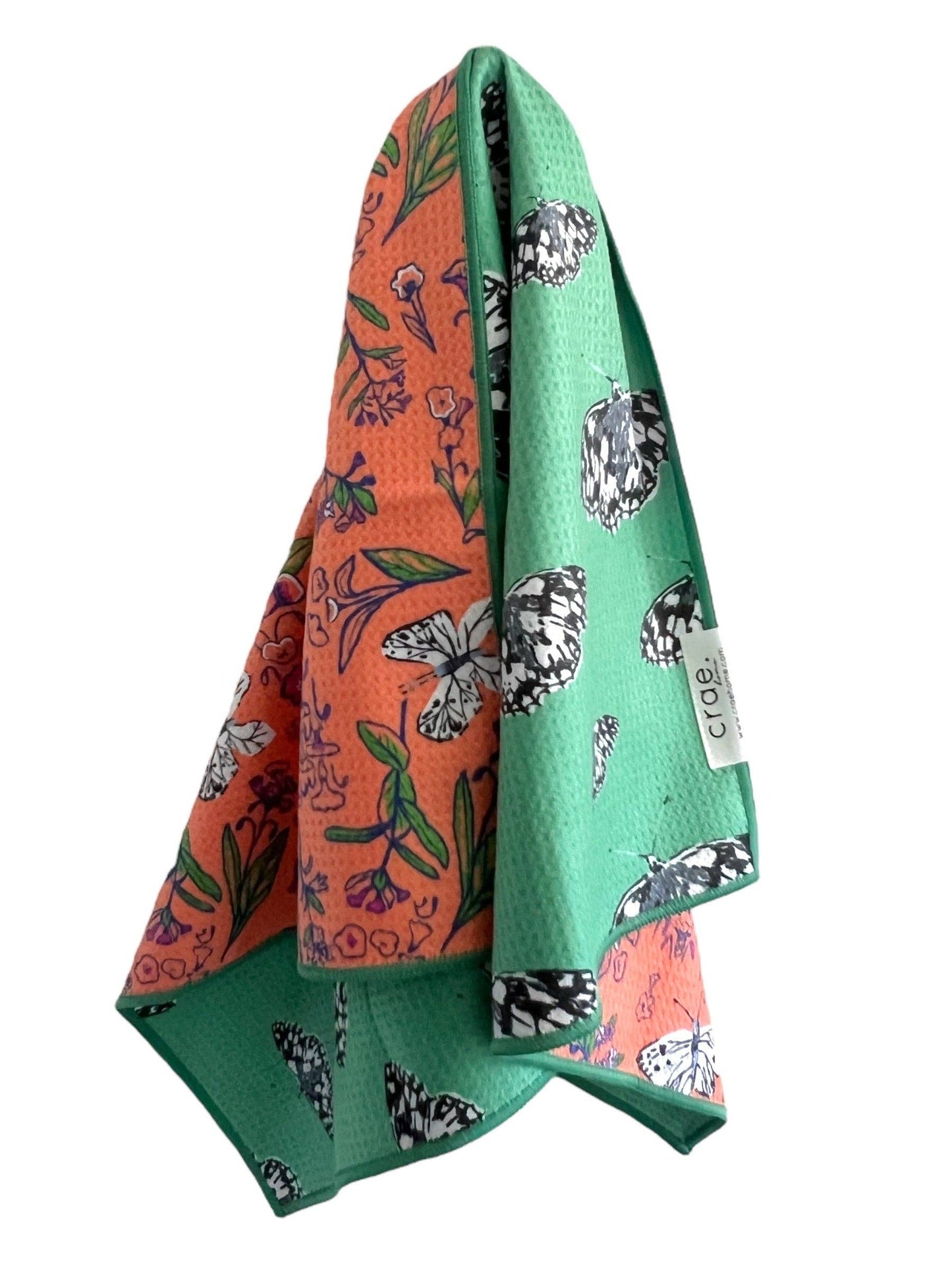 Two fabric swatches, one orange with floral and butterfly pattern, the other green with similar patterns, on a white background.