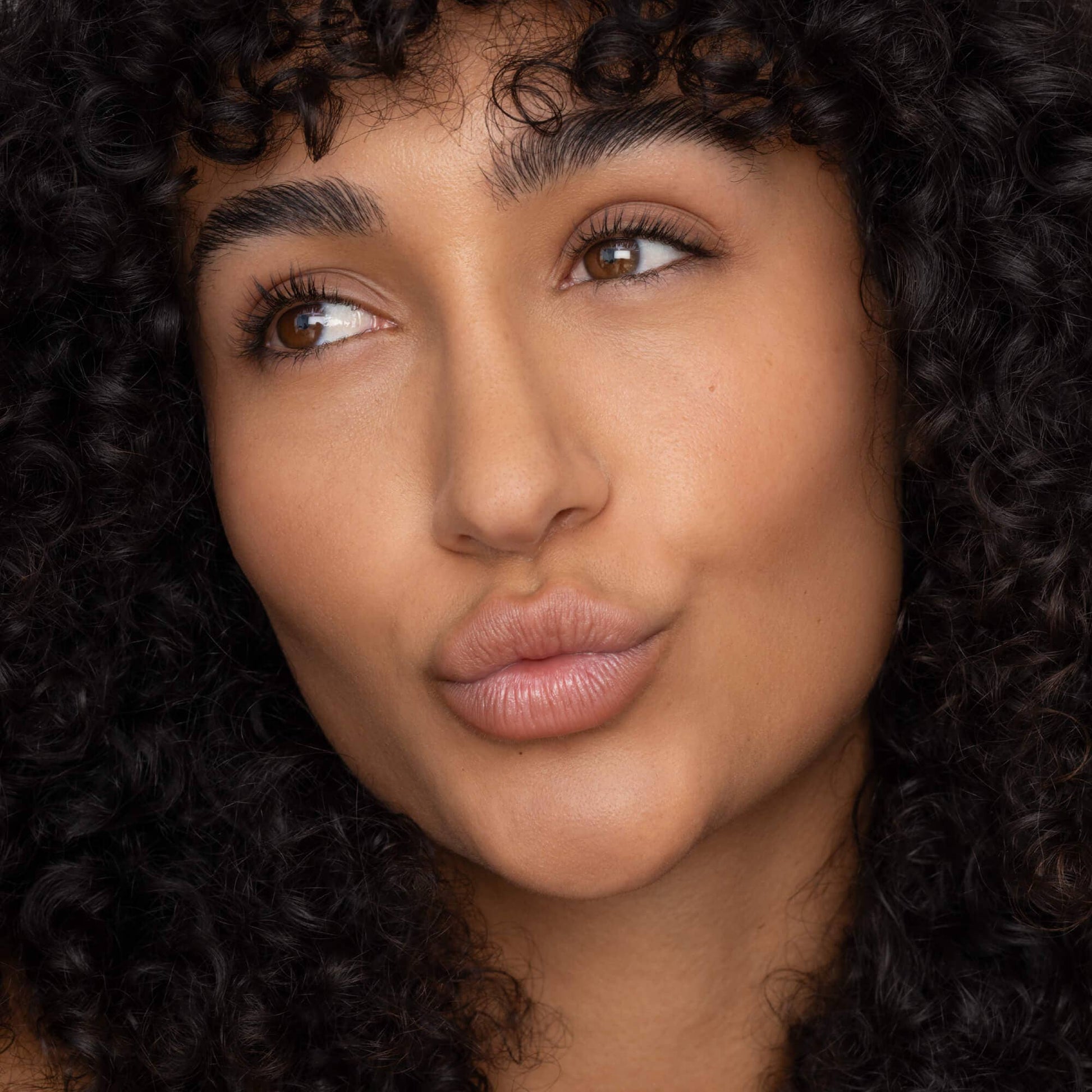 Close-up of a person with curly hair, focusing on the face.