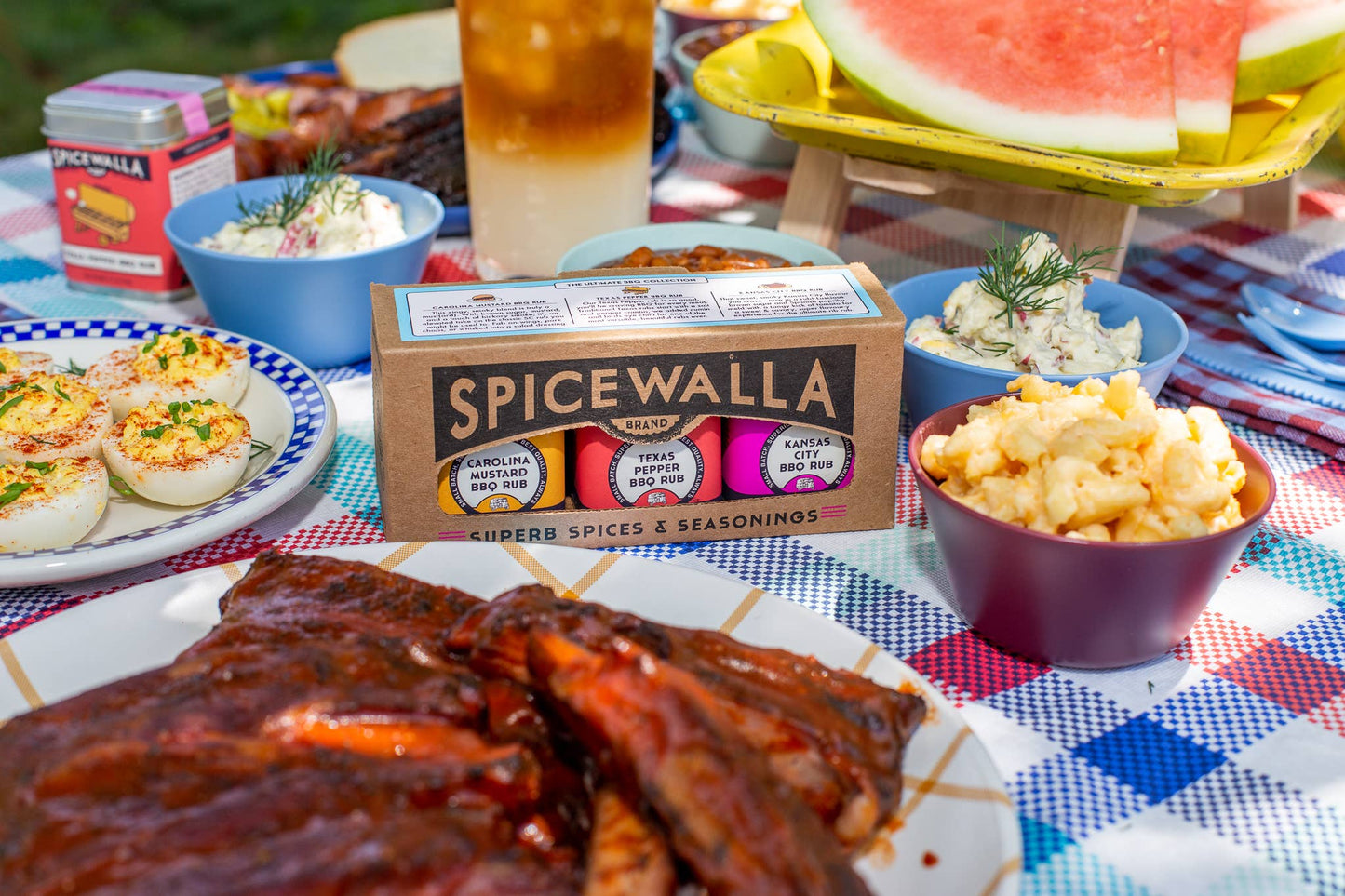 Spicewalla seasoning mix on a picnic table with food and drinks