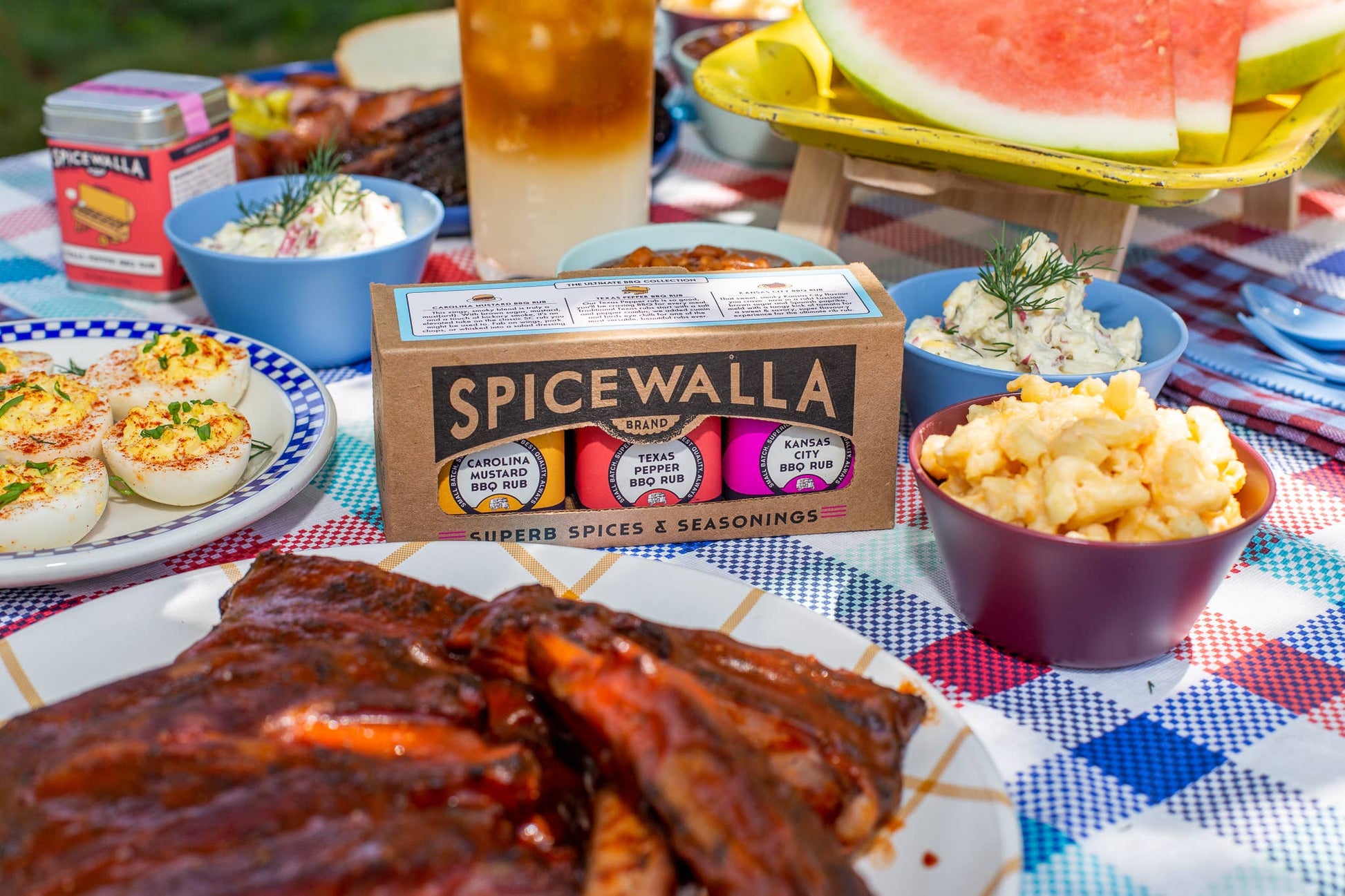 Spicewalla seasoning mix on a picnic table with food and drinks