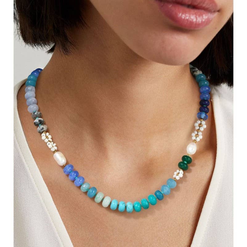 Necklace with blue and green beads and pearls worn by a person