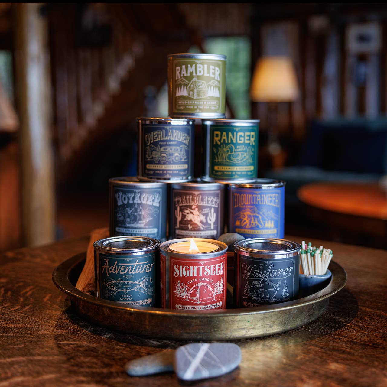 Collection of candles in metal cans with visible branding on a wooden surface.