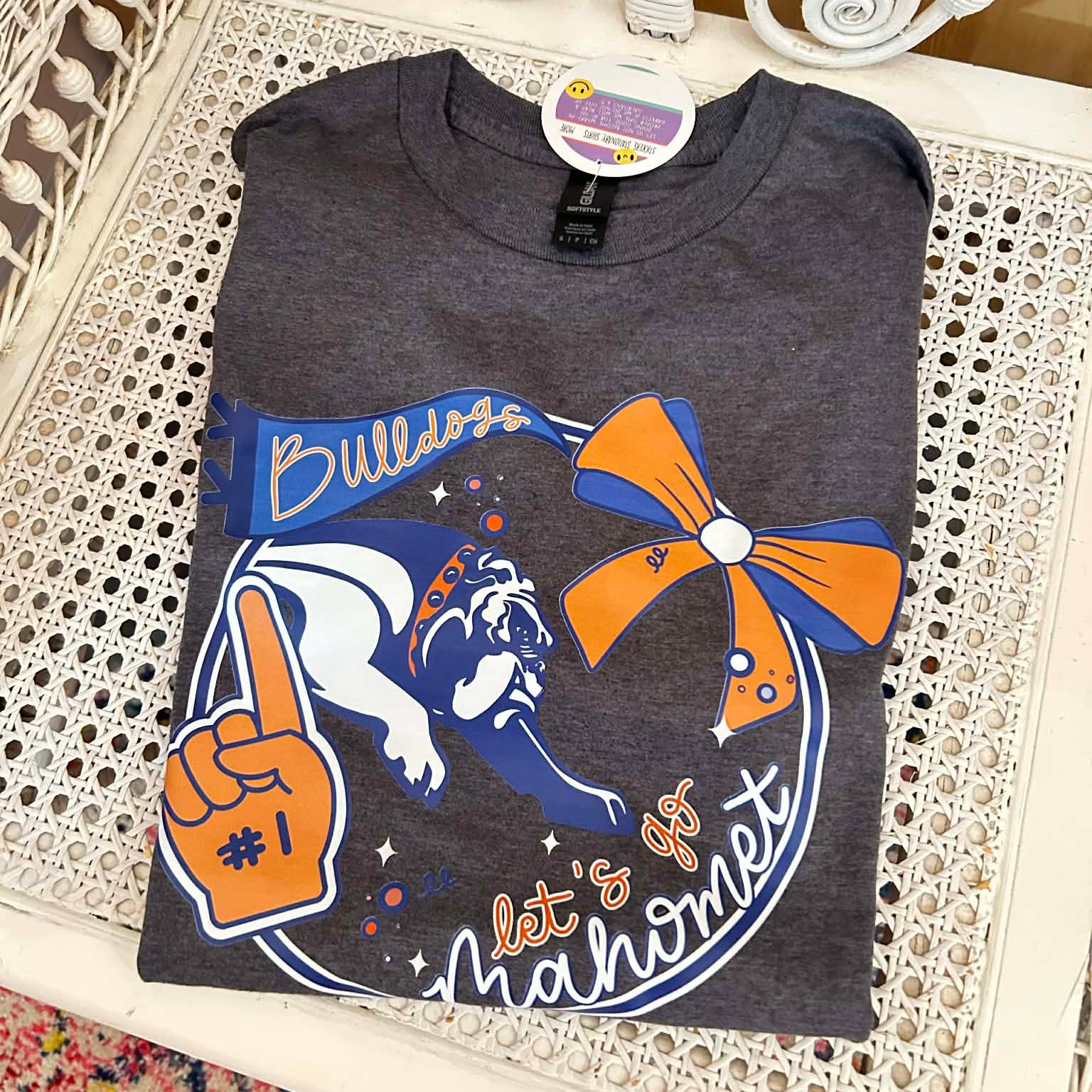Folded t-shirt with bulldog and cheerleading design on a decorative chair.