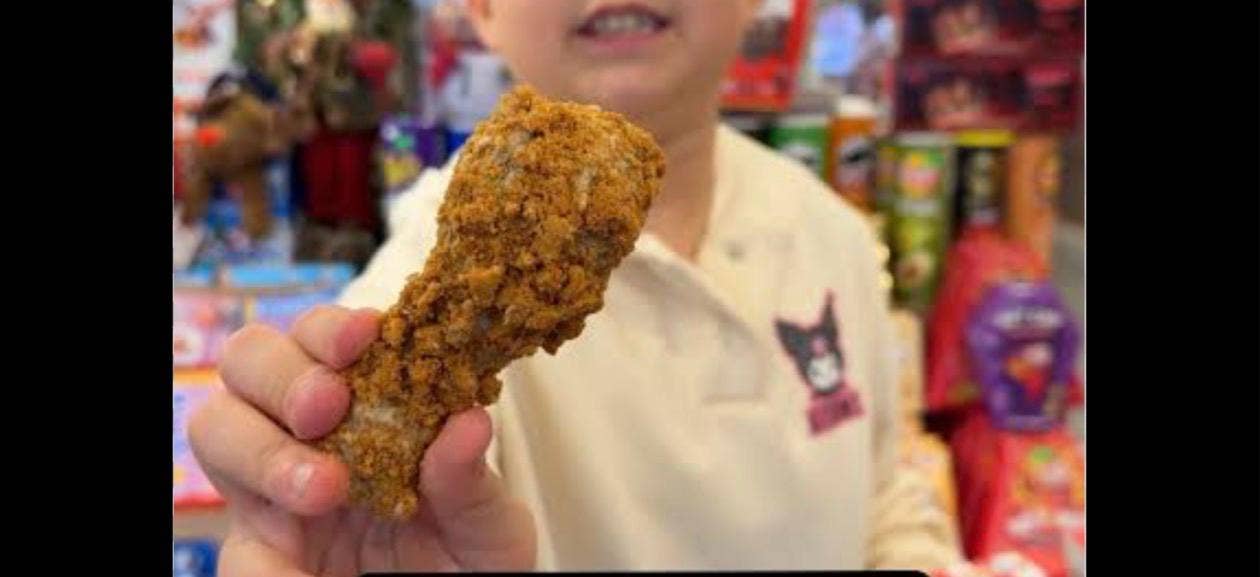 Child holding a large fried chicken drumstick in a store setting