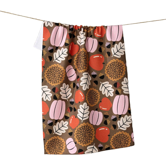 Decorative blanket with autumnal pattern hanging on a line against a neutral background