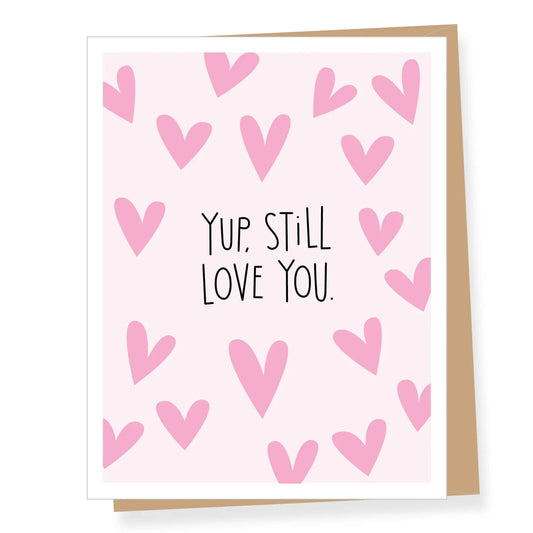 Valentine's Greeting card that states 'yup,still love you.' Light pink background with darker pink hearts and black letering. Envelope is kraft brown.